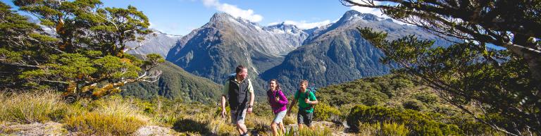 Guide and walkers in mountain scenery - Fiordland National Park Tours