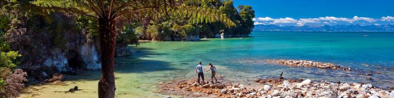 Walkers barefoot on the shore - Abel Tasman National Park Tours